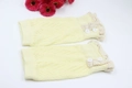 Detail of light yellow knit leg warmer with lace trim and two white buttons - Beige