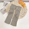 Kids grey knitted leg warmers with bows and pom-poms on a rustic autumn background - One Size / Light Gray