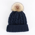 Close-up of thick cable knit texture on dark blue beanie with a large faux fur pompom - One Size / Navy Blue
