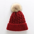 Detail of burgundy thick cable knit hat featuring a fluffy light brown faux fur pompom - One Size / Burgundy