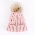 Close-up of pink knit beanie featuring chunky cable pattern and large faux fur pompom - One Size / Pink