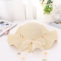 Dettaglio di un cappello di paglia beige con fiocco in tulle, perle e delicati fiori decorativi - Taglia unica / Beige