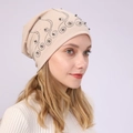 Close-up of soft beige cotton beanie featuring intricate silver bead and rhinestone patterns - Beige