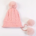 Detail of light pink chunky cable knit beanie with fluffy pom-poms and braided chin straps - Pink