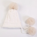 Detail of soft white cable-knit hat featuring three large fluffy faux fur pom-poms - White