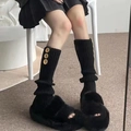 Detail of black ribbed leg warmers with gold buttons paired with plush faux fur slippers - Black