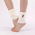 Detailed knit texture of cable-knit leg warmers with vintage brown buttons in cream white - White