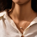 Detalle de collar de perlas de plata s925 lucido por modelo en camisa de lino - Cadena dorada-Perla única con cuentas doradas