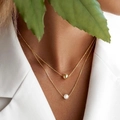 Detalle de collar de doble capa en plata S925 con perla y cuenta dorada puesto en modelo - Doble capa dorada-Cuenta redonda y perla de agua dulce