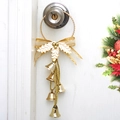 Nahaufnahme von goldenen Weihnachtsglocken mit Schleife an einem weißen Türgriff - Gold