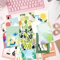 Flat lay di cartoline artistiche botaniche accanto a una tastiera rosa su una scrivania - Carte Da Parete Fresche Con Motivi Floreali (T01041526)