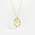 Macro detail of gold necklace featuring letter W pendant with colorful cubic zirconia - Letter W