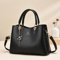 Schwarze Handtasche mit Blumenanhänger, goldener Hardware und Umhängeriemen - Schwarz