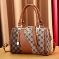 Minimalistische Boston-Handtasche mit Monogramm-Canvas und breitem Gurt auf Holztisch - Mittel / Patchwork Braun