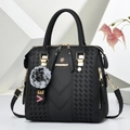 Classic black leather handbag with V-weave pattern and fuzzy pom pom keychain accessory - Black