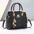 Detail of black pebbled faux leather handbag featuring a colorful tassel and gold-tone hardware - Black