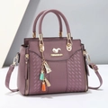 Detail of mauve pebbled leather handbag with woven texture and colorful tassel charm - Purple
