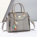 Detail of grey lychee texture handbag with gold hardware, squirrel logo and colorful tassel - Gray