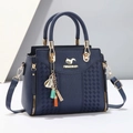 Detail of navy blue leather handbag featuring woven texture and gold squirrel logo - Blue