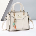 Detalle de bolso de cuero marfil con textura trenzada y colgante de borlas coloridas - Blanco Roto