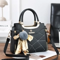 Close-up of black pebble leather handbag with gold metal logo and silk ribbon charm - 23.5cm x 9cm x 19cm (11cm Handle) / Black