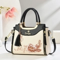 Elegante bolso blanco roto con bordado floral, borlas negras y colgante de gato dorado - Negro