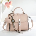 Close-up of pink litchi grain leather handbag with silver twist lock and heart charm - Pink