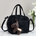 Detail of black suede tote bag with brown horse charm and versatile shoulder strap - Black