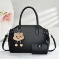 Close-up of black litchi grain leather tote bag set with cute plush charm and silver hardware - Black