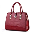 Détail d'un sac à main bordeaux en cuir verni avec motif crocodile et garniture dorée - Bordeaux