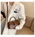 Detail of dark brown vintage faux leather handbag with buckle being worn by a model - Brown