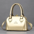 Golden metallic top-handle bag with logo and jewel clasp on grey background - One Size / Champagne