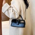 Vintage black embossed leather handbag with gold buckle shown on minimalist model coat - Black