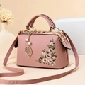 Detail of pink leather handbag featuring floral embroidery and golden leaf pendant - Pink