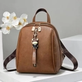 Detalle de mochila de cuero marrón caramelo con colgante de toro y cremalleras doradas - Marrón