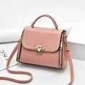 Sac bandoulière rose avec fermoir doré et surpiqûres blanches sur un présentoir épuré - Rose
