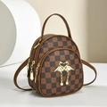 Close-up of checkerboard shoulder bag featuring golden swan hardware and pearl charms - Coffee