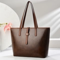Bolso tote minimalista marrón oscuro con correas claras y hebillas doradas en estudio - café