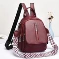 Détail d'un sac à dos bordeaux en cuir avec une large bandoulière à motifs géométriques - Bordeaux