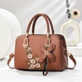 Detailed close-up of brown faux leather bag featuring floral embroidery and gold hardware - Earthy Yellow