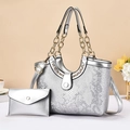 Silver snakeskin embossed handbag set with gold chunky chain handle in a lifestyle setting - Silver