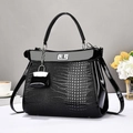 Black crocodile embossed handbag with silver clasp and mini bag charm accessory - Black