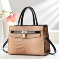 Detailed macro view of brown crocodile texture and gold hardware on the commuter handbag - Khaki