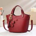 Detailed macro view of burgundy lychee leather bucket bag with gold hardware and flower charm - 20*12*19cm / Burgundy