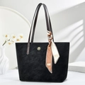 Large black tote bag with decorative silk scarf and gold logo in an elegant setting - Black