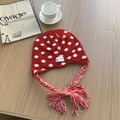 Gorro de punto con lunares rojos, orejeras y borlas sobre una superficie de madera - Rojo
