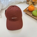 Dark red cotton baseball cap with white script embroidery in a cozy setting - Burgundy