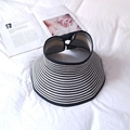 Detailed top view of black and white striped sun hat with wide brim on white fabric - Black