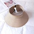 Detail of striped straw sun hat with wide brim and open top on a white fabric background - Khaki