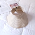 Detail view of foldable straw visor with adjustable strap on white textured background - Beige